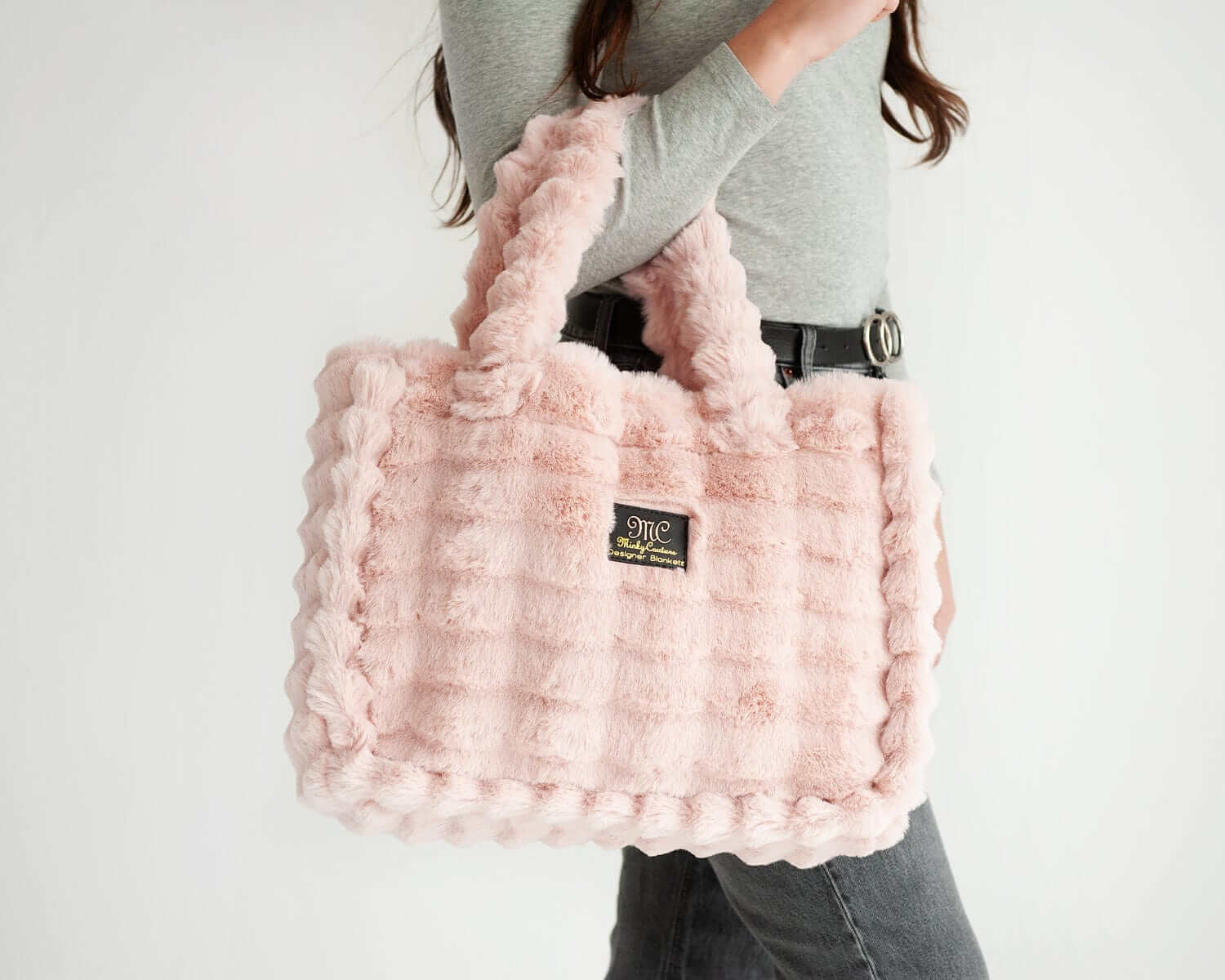 Woman holding the Ripple Blush Annie Bag, a stylish and luxurious pink handbag with a textured design.