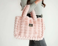 Woman holding the Ripple Blush Annie Bag, a stylish and luxurious pink handbag with a textured design.