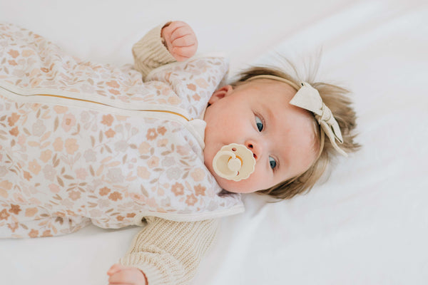 Infant in Dainty Floral Wearable Minky Blanket, featuring soft pink and blue floral design and a gold zipper.