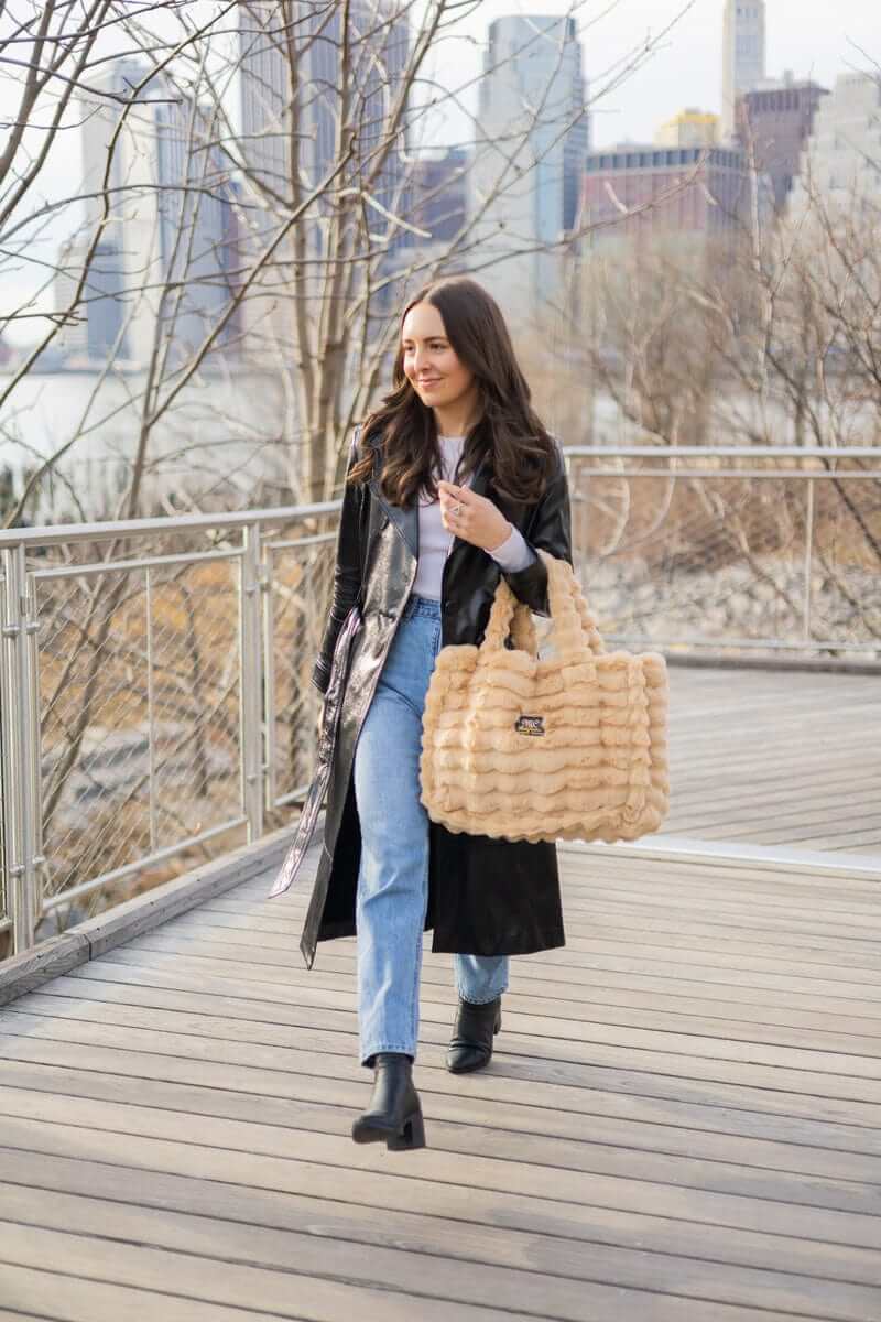 Model walking on a bridge in the city carrying the Annie Bag Ripple Ecru, showcasing its stylish design and texture.