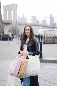 Model showcasing the Annie Bag Ripple Cream in a stylish urban setting with Brooklyn Bridge in the background.