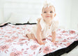 Baby girl sitting on a blush pink Apricot Blossom blanket .