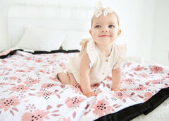 Baby girl sitting on a blush pink Apricot Blossom blanket .
