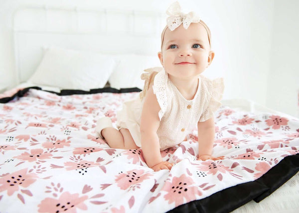 Baby girl sitting on a blush pink Apricot Blossom blanket .