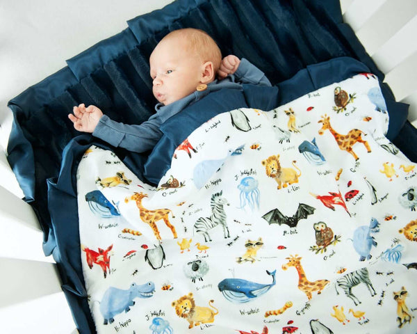 Baby in a ABC Zoo Blanket with zoo animals and their names on it.