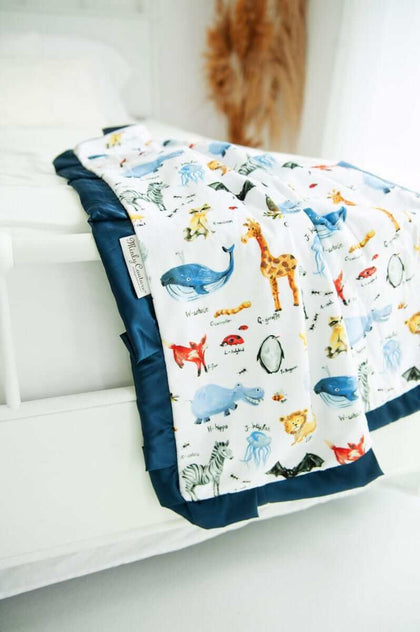 ABC Zoo animal themed blanket draped over the end of a bed. 