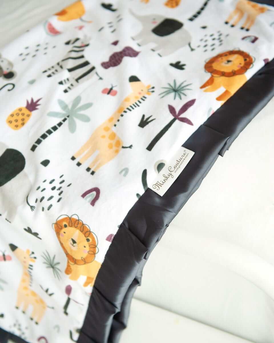 Cartoon zoo animal themed blanket laying off the end of a bed. 