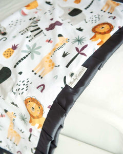 Cartoon zoo animal themed blanket laying off the end of a bed. 