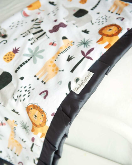 Cartoon zoo animal themed blanket laying off the end of a bed. 