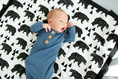 Newborn baby laying on top of a bear patterned blanket. 