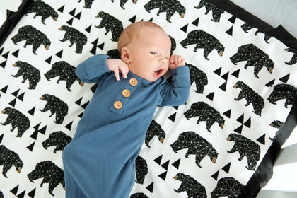 Newborn baby laying on top of a bear patterned blanket. 