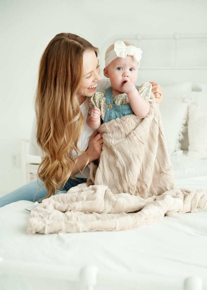 Mom and baby enjoying cozy moments with Sorbet Almond Croissant Blanket on a bed.