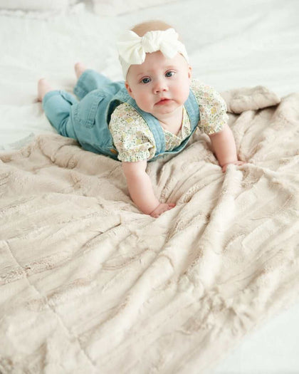 Baby lying on Sorbet Almond Croissant Blanket, showcasing its soft texture and warm almond hue.