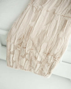 Soft and textured Sorbet Almond Croissant Blanket draped elegantly over a bed.