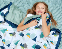 Young girl smiling while wrapped in the Mountain Tops Blanket, showcasing its cozy design and mountain-themed patterns.