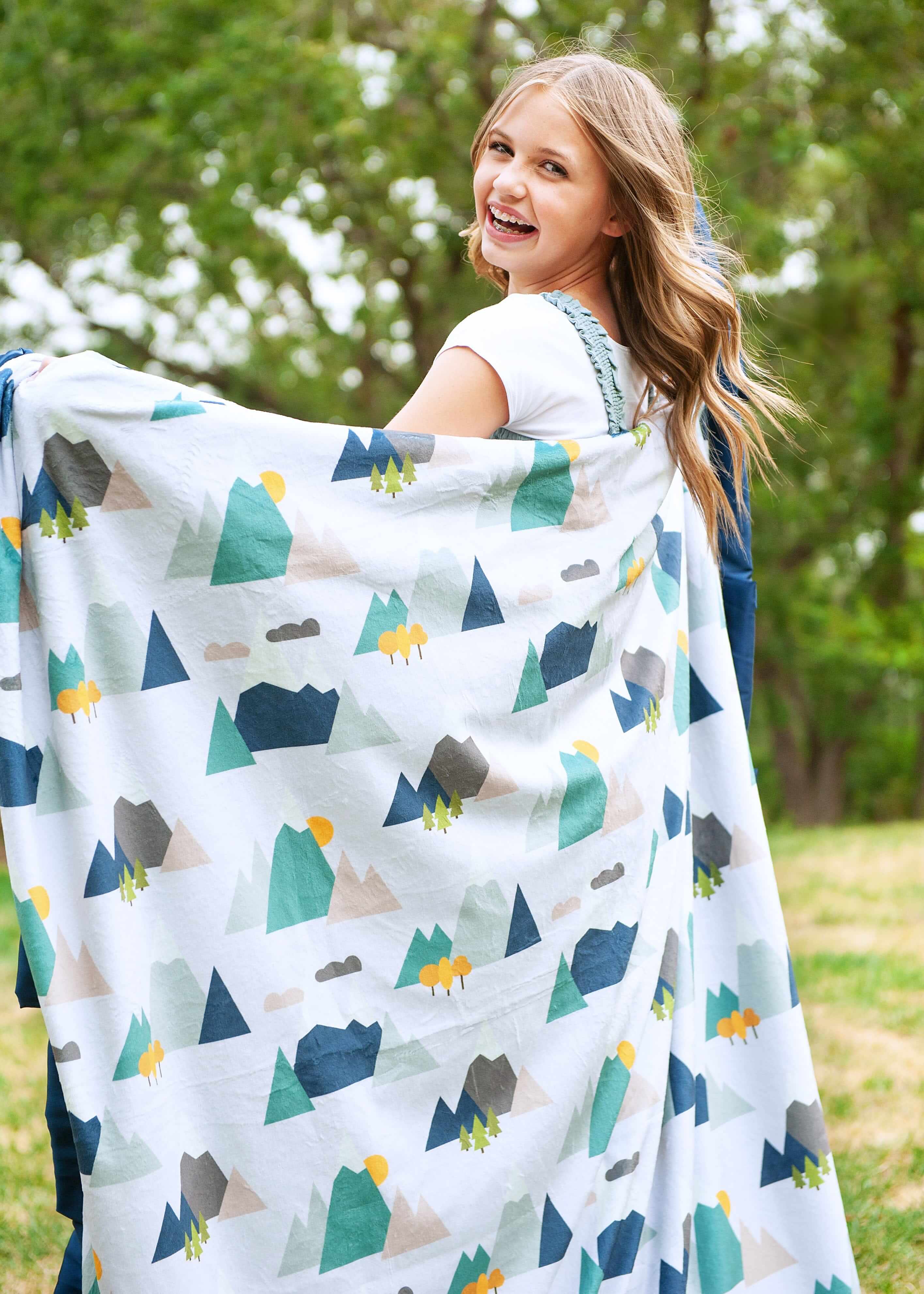 Girl twirling with a mountain top themed blanket by Minky Couture.