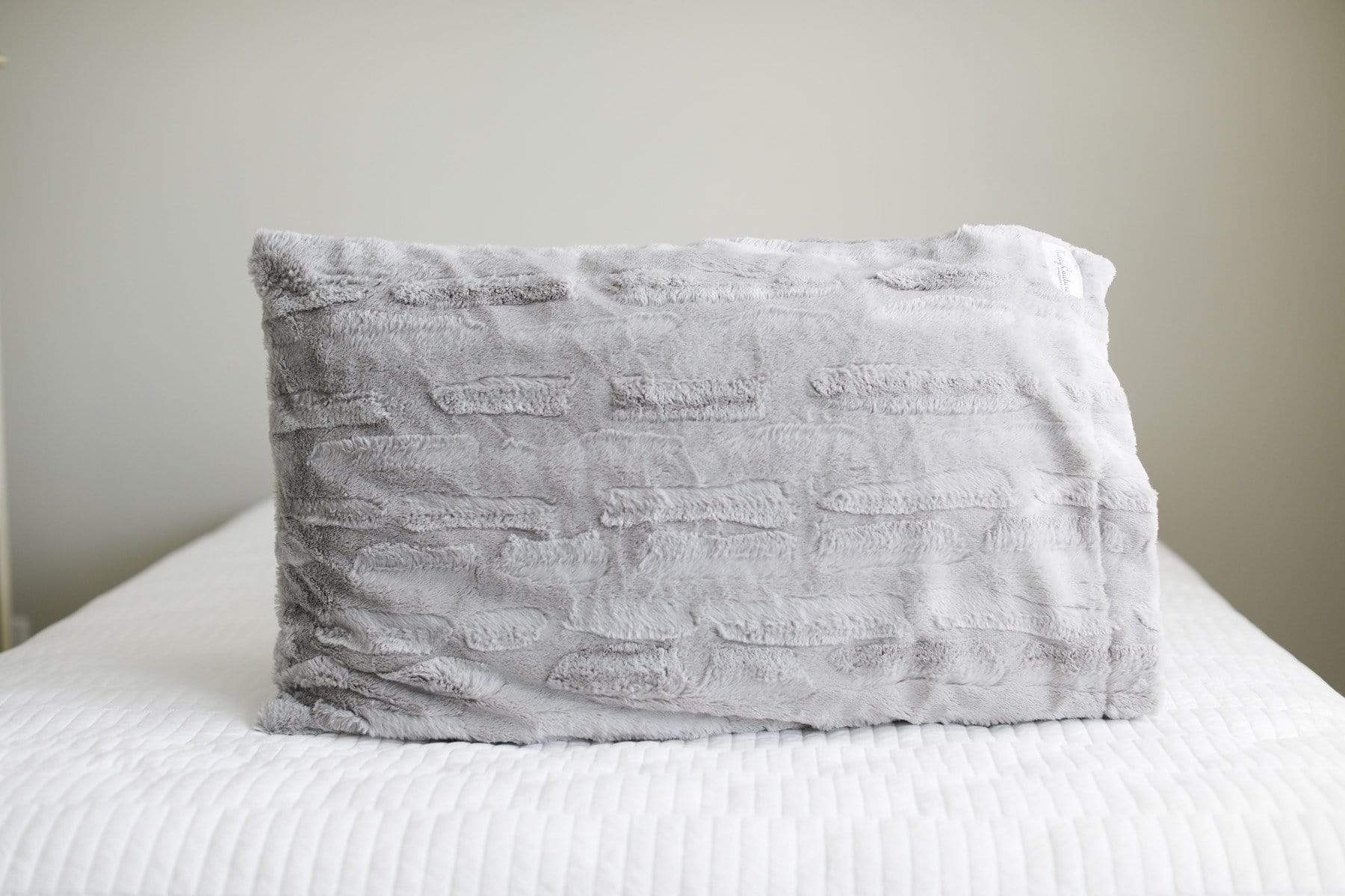 Silver | Light gray plush Minky Couture pillowcase sitting on a bed. 
