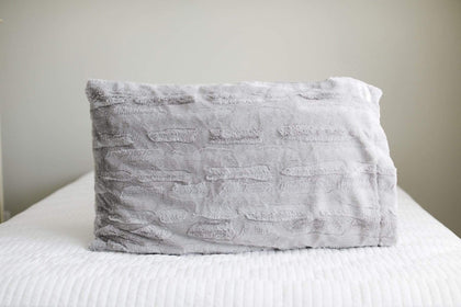 Silver | Light gray plush Minky Couture pillowcase sitting on a bed. 