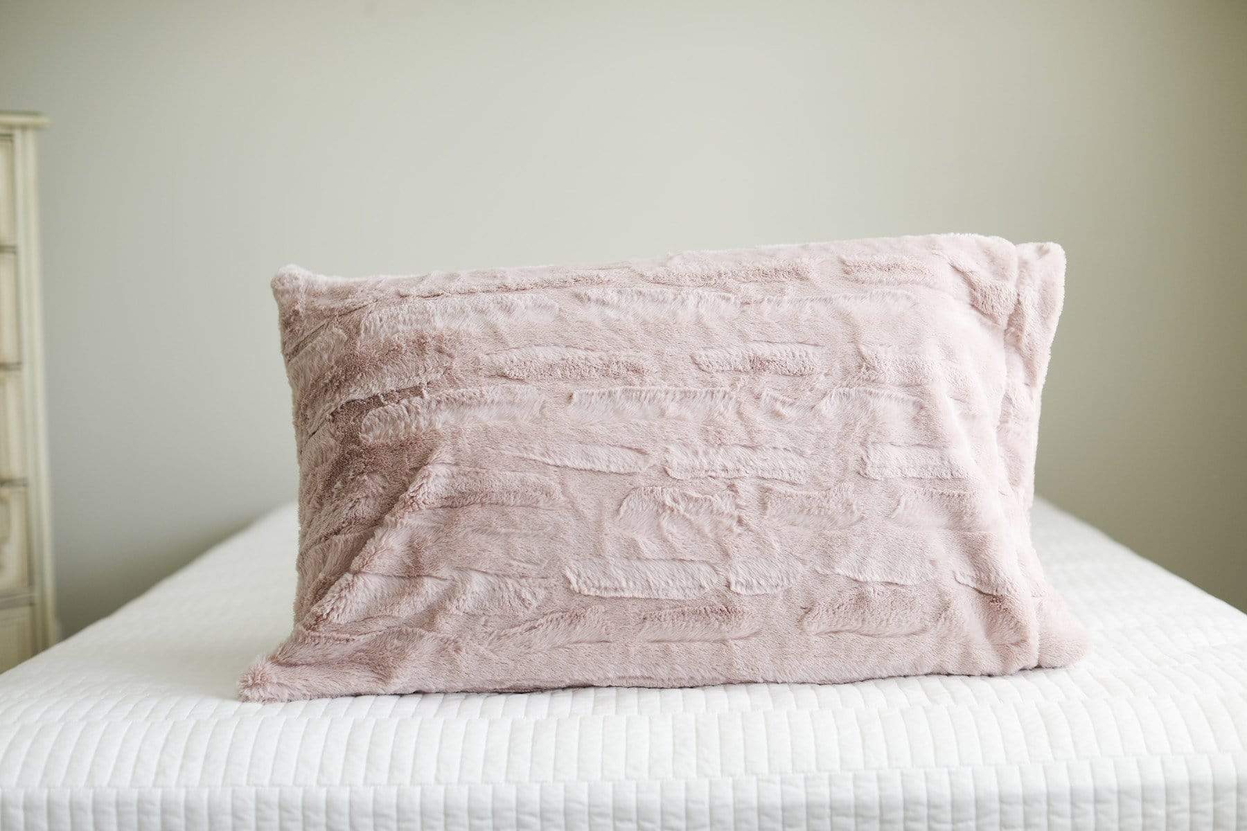Blush | Blush pink plush Minky Couture pillow sitting on a bed. 