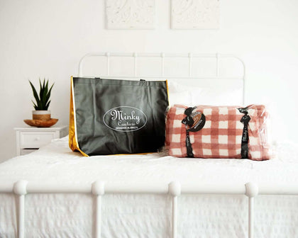 Reusable Shopping Bag from Minky Couture next to a wrapped blanket on a bed.