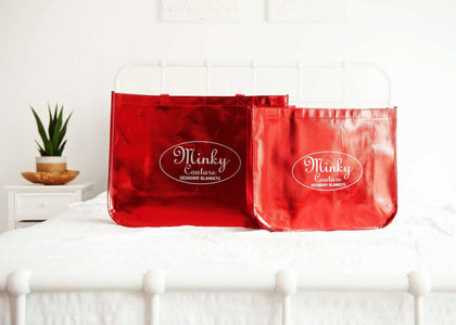 Shopping Bag: Minky Couture's reusable red shopping bags displayed on a bed, perfect for gifts and groceries.