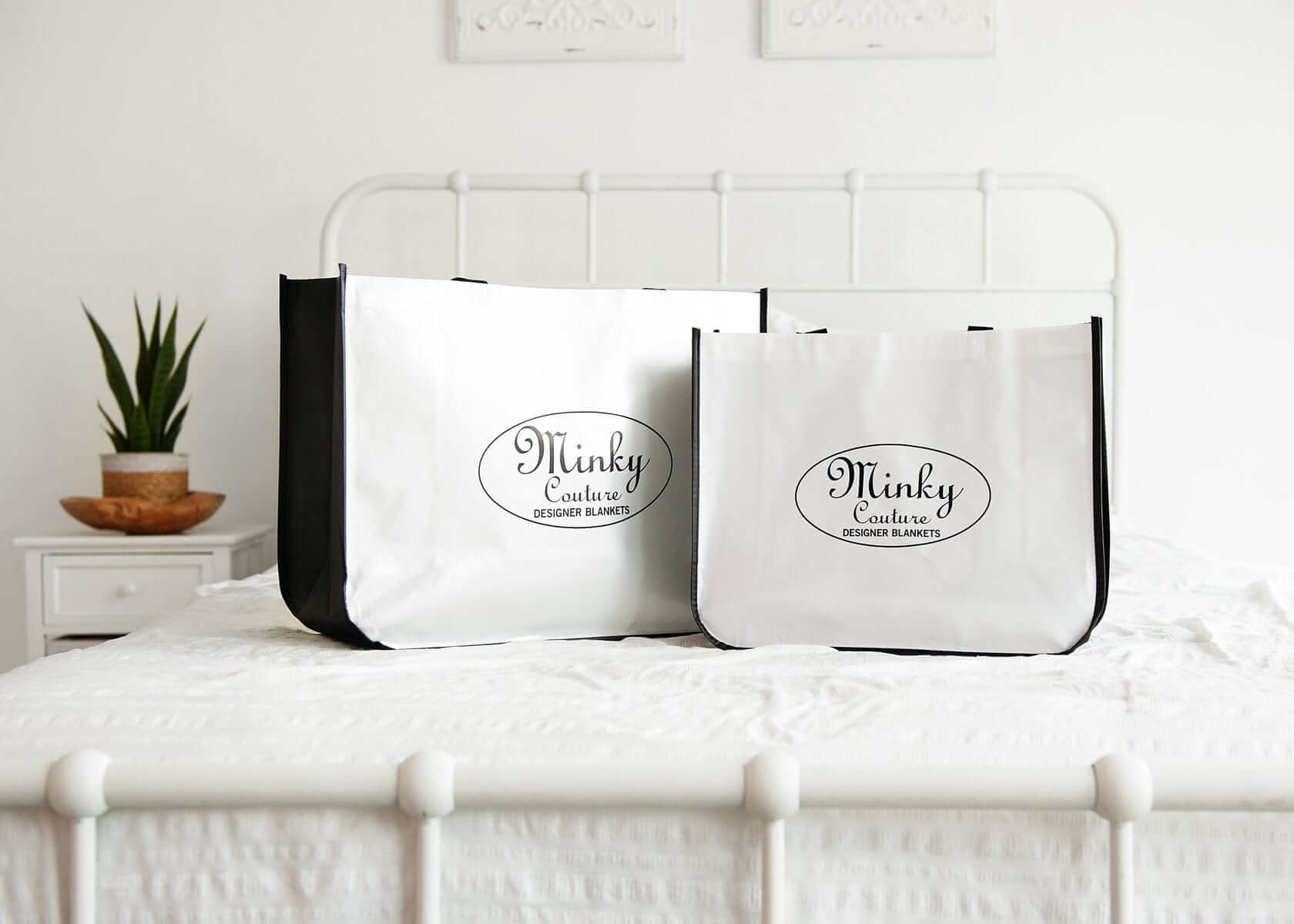 Two Minky Couture reusable Shopping Bags displayed on a bed, showcasing their design and versatility for various uses.