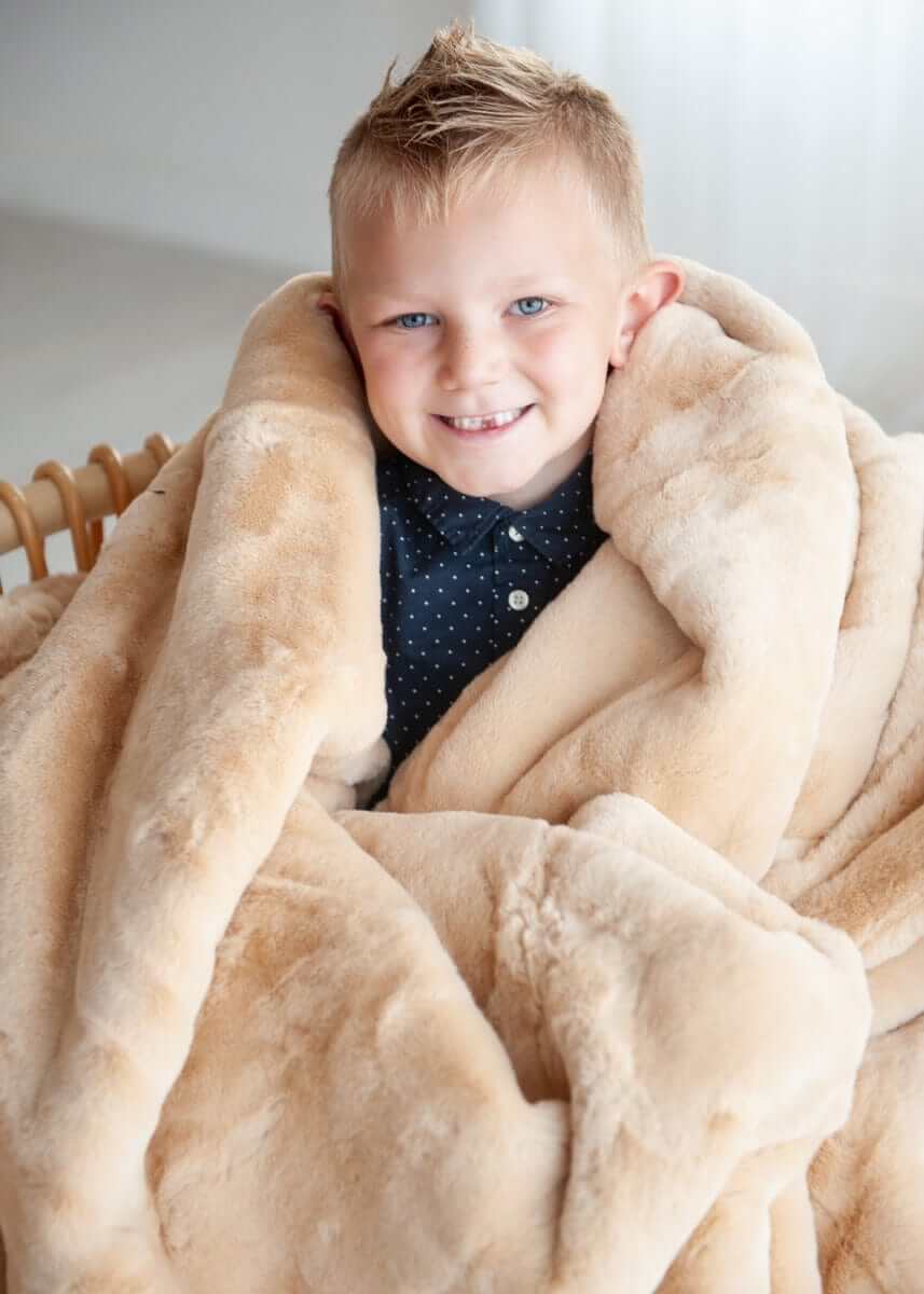 Child wrapped in Lush True Caramel Blanket, enjoying its soft and cozy texture.