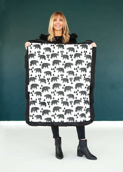 Woman standing holding a small My Bear patterned blanket.