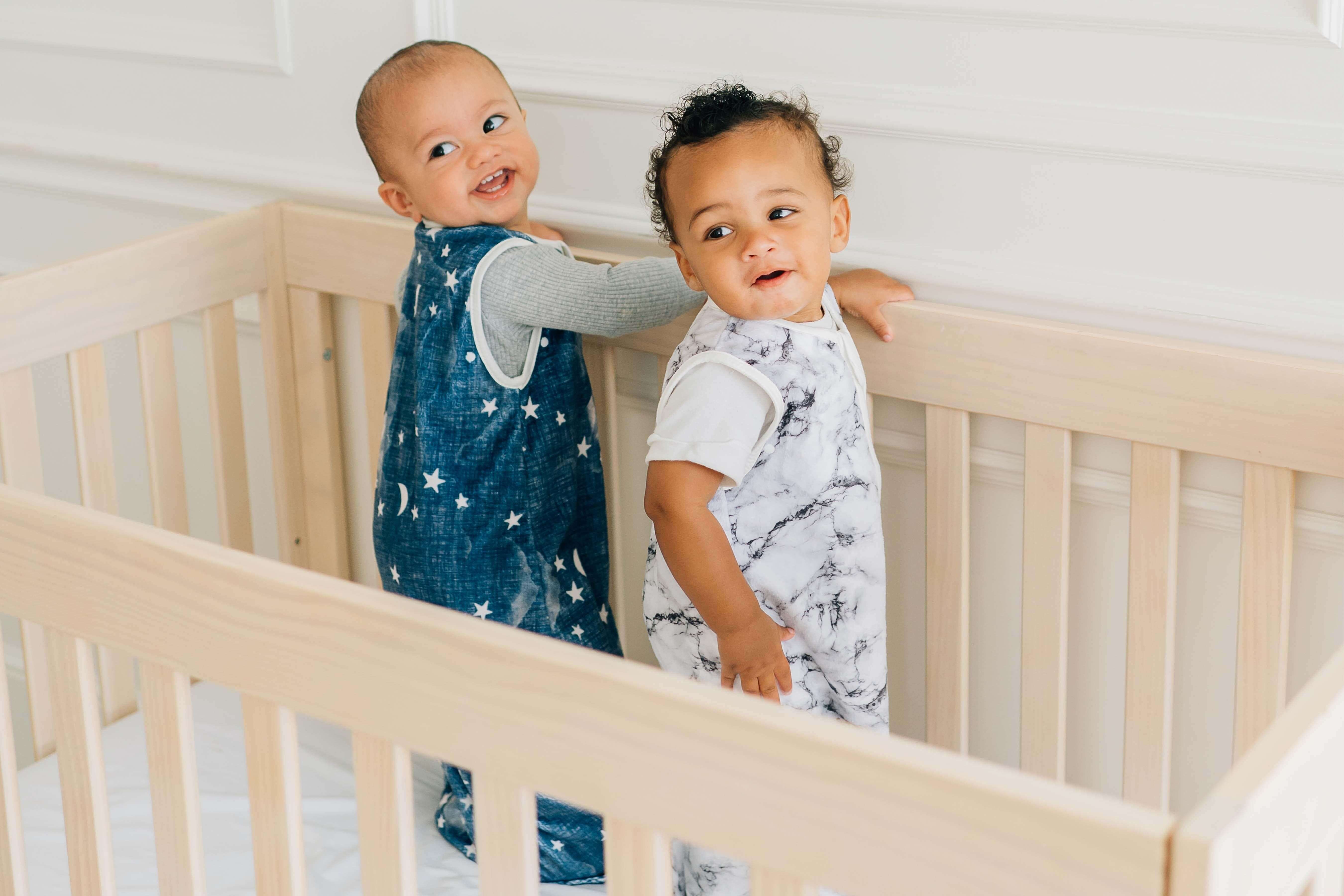 Babies wearing Navy Stars and Moons Wearable Minky Blanket in a crib, smiling and safe.