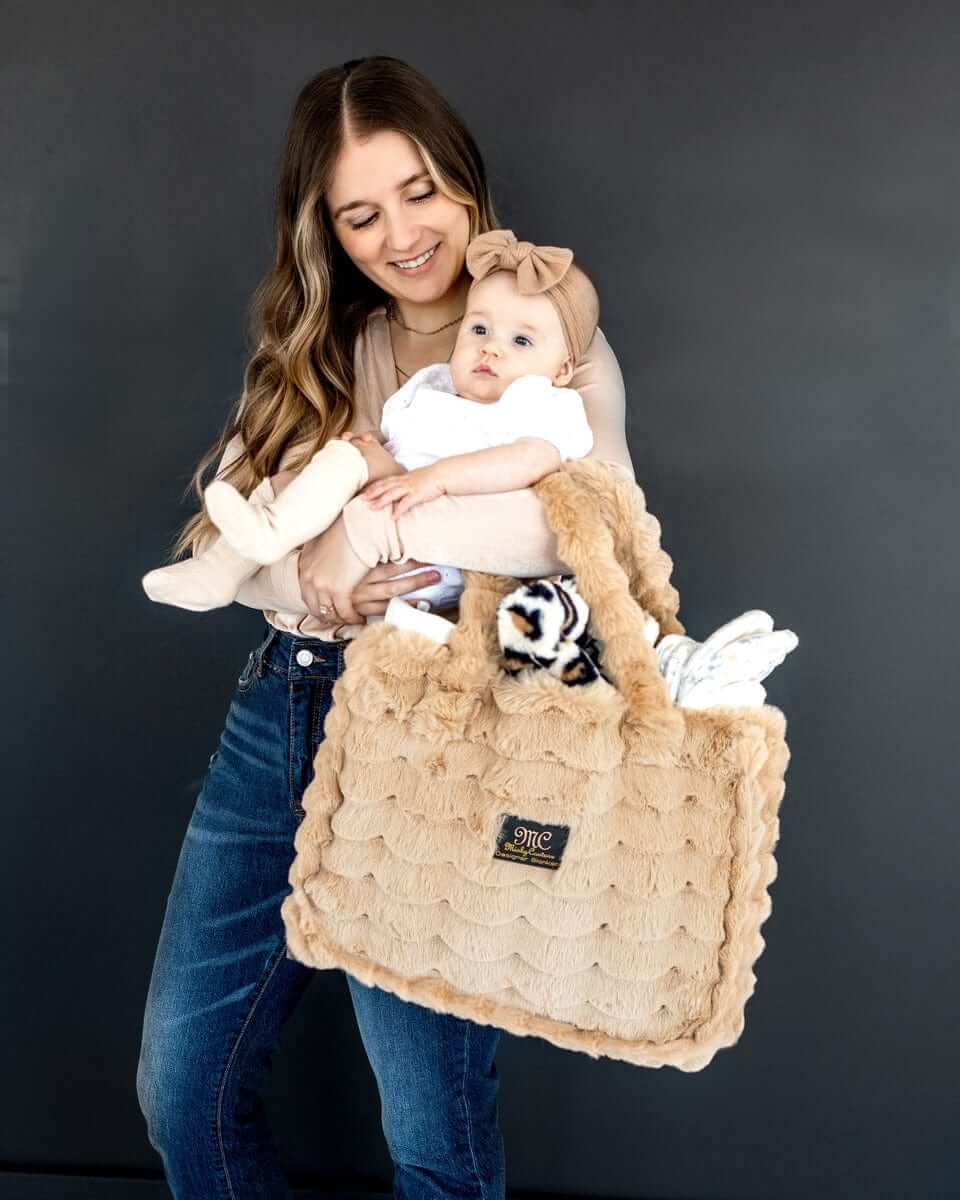 Woman holding a baby with the Annie Bag Ripple Ecru, showcasing its luxurious texture and stylish design.