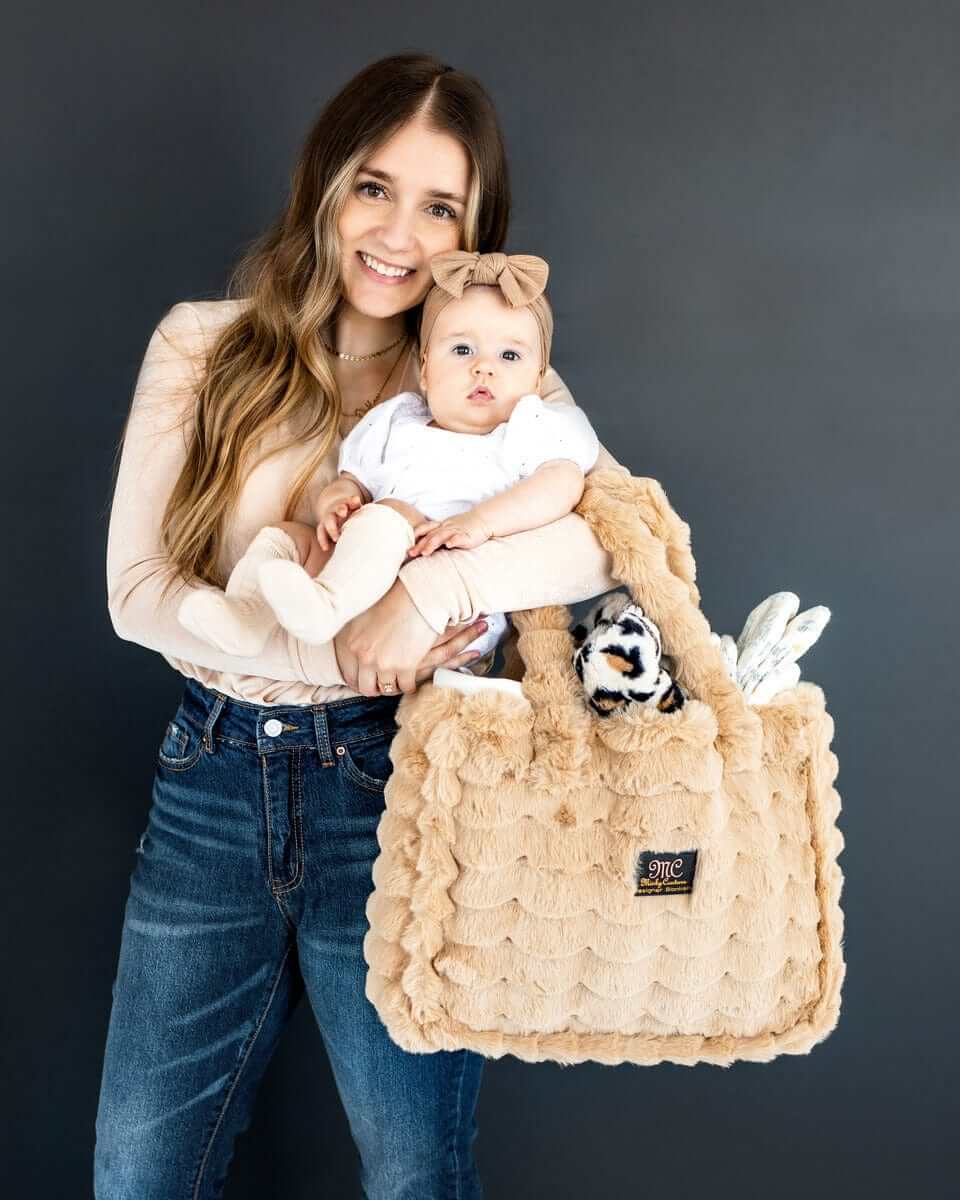 Woman holding baby with Annie Bag Ripple Ecru, a stylish and functional accessory, perfect for any occasion.