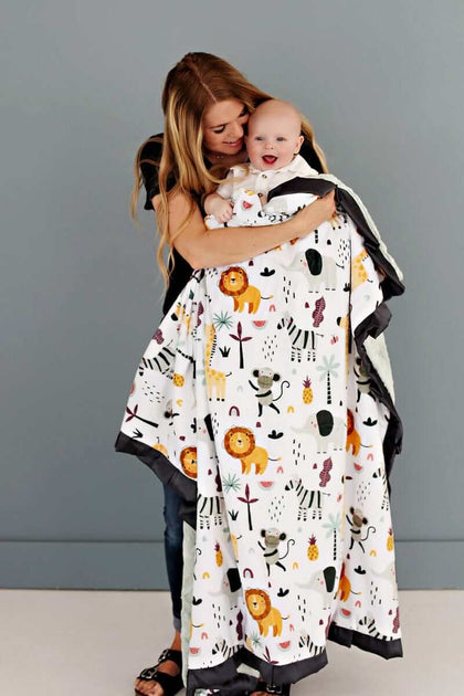 Mother holding her baby boy in a cartoon zoo animal patterned Minky Couture blanket.
