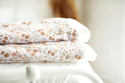 Dainty Floral Blanket featuring delicate pink and beige flowers on a soft white fabric.