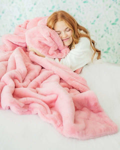A woman enjoying the comfort of the Lush Pretty Pink Blanket, wrapped in its soft, feminine hue.