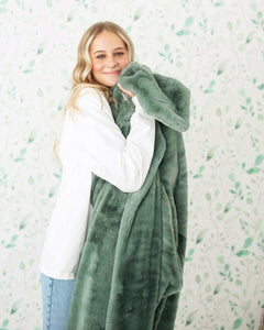 Lush Midnight Mist Blanket displayed by a young woman holding the soft green plush blanket, showcasing its cozy texture.