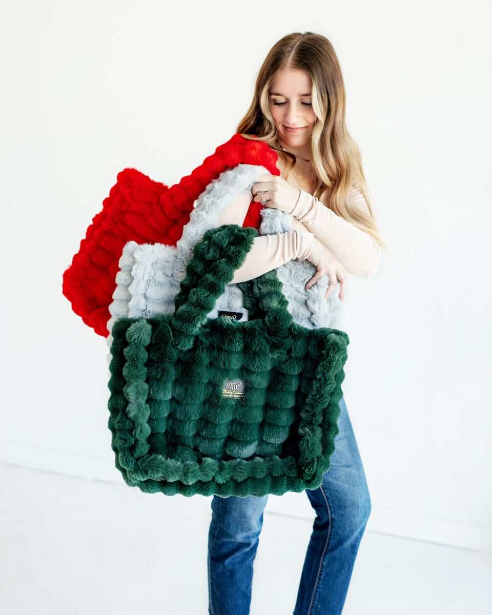 Woman showcasing multiple Annie Bags in various colors and textures, embodying luxury and style.